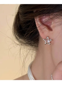 Close-up of star-shaped S999 silver stud earring with zircon inlay worn on ear