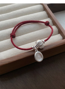 Close-up of S925 silver snake charm and red woven bracelet with engraved lucky pendant