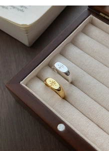 Detail of gold and silver S925 rings featuring etched starburst designs on a velvet cushion