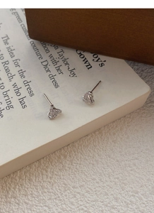 Macro shot of silver twisted knot stud earrings with micro-set crystals on book background