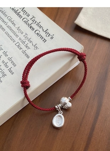 Macro detail of S925 silver charms on red woven bracelet with Chinese characters