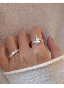 Detail of matte silver gourd ring and zircon band on model wearing beige knit sweater