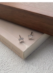 Nahaufnahme von Katzenpfoten-Ohrsteckern aus Silber mit Zirkon-Inlay auf einem Buch