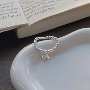 Bague en perles d'argent S925 avec breloque poisson et pendentif sur un plateau blanc