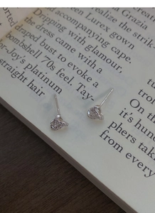 Detailed close-up of S999 sterling silver knot earrings with pavé zircon on vintage book