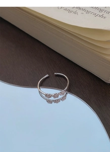 Nahaufnahme eines S925 Sterlingsilberrings mit drei kleinen Pflaumenblüten auf Spiegel