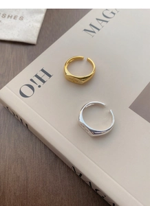 Detail of gold and silver S925 sterling silver starburst signet rings on a magazine