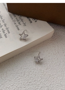 Detail of S999 sterling silver star stud earrings with cubic zirconia on vintage book