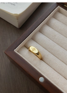 Macro detail of gold oval signet ring with starburst engraving in jewelry box