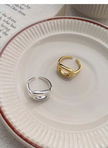 Macro shot of minimalist oval hollow rings in silver and gold on a ceramic tray