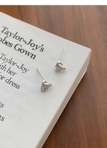 Detailed view of silver heart stud earrings with sparkling pave-set stones on paper