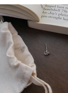Macro shot of silver geometric triangle stud earrings with zircons and a fabric pouch