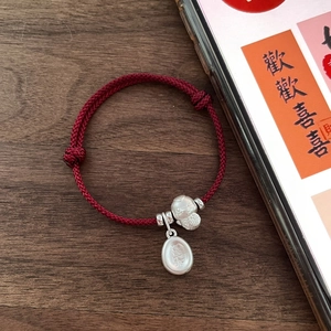 S925 silver snake year red woven bracelet with lucky charms on dark wooden desk