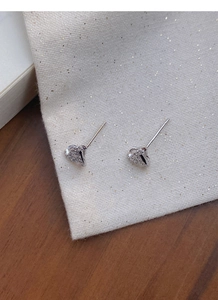 Close-up of heart-shaped silver earrings with sparkling cubic zirconia on gold fabric