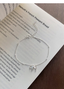 Dettaglio del bracciale in argento S925 con fiocco e perline su un libro vintage