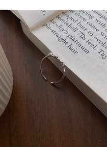 Nahaufnahme eines S925 Silberrings mit drei Blumen auf einem offenen Buch