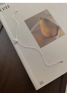 Dettaglio del bracciale con fiocco in argento sterling S925 su libro con punzone