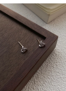 Detailed view of silver twist earrings with pavé set white zircon stones on wood