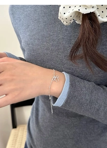 Dettaglio del bracciale fiocco in argento S925 al polso con elegante maglione di maglia