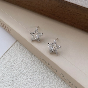 Elegant S999 silver star stud earrings with sparkling cubic zirconia on a book