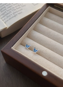 Dettaglio di orecchini a farfalla in argento S999 su una scatola di gioielli vintage