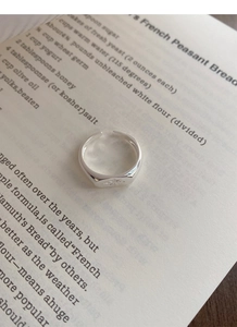 Macro shot of silver adjustable star ring on book pages showing detailed star engraving