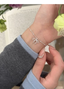 Dettaglio macro di un bracciale minimalista in argento sterling S925 con ciondolo a fiocco