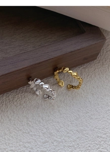 Detailed view of silver and gold heart-shaped adjustable open rings on a textured fabric