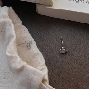 S999 sterling silver knot earrings with pavé zircons on a wooden surface with a fabric pouch