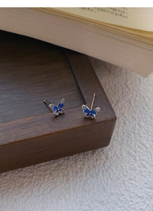 Dettaglio di orecchini a farfalla in argento con smalto blu e piccoli zirconi brillanti