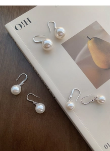 Gros plan de boucles d'oreilles en argent S999 et perles au fini brillant sur magazine