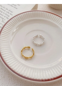 Detail of adjustable heart rings in gold and silver finish on a ceramic dish