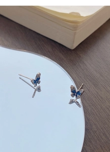Dettaglio macro di orecchini a farfalla in argento con smalto blu e riflesso nitido