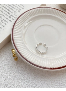 Detail of adjustable heart chain rings in silver and gold on a ceramic tray