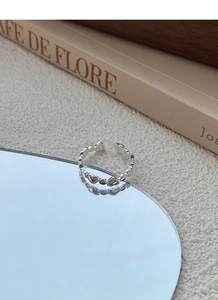 Macro detail of silver heart-shaped adjustable ring on a mirror with soft reflections