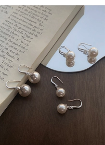 Vue détaillée de boucles d'oreilles en perles et argent sterling S999 sur bois sombre