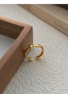 Detail of adjustable gold heart ring featuring interlocking hearts on a warm background