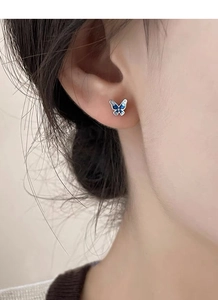 Dettaglio dell'orecchino a farfalla blu in smalto indossato da una modella