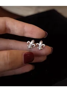 Macro shot of S925 sterling silver fleur-de-lis stud earrings with matte brushed finish