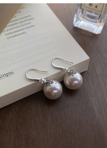 Vue macro de boucles d'oreilles en perles S999 et zircon feuille d'érable sur livre