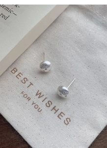 Macro shot of S925 sterling silver ball studs with star engravings on linen pouch