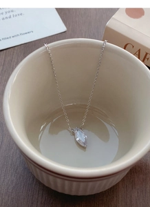 Close-up of S925 sterling silver marquise necklace hanging on a ceramic cup