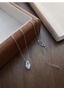 Detailed view of S925 sterling silver marquise necklace on a wooden tray with a book