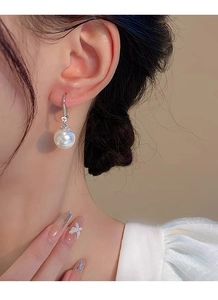 Gros plan sur d'élégantes boucles d'oreilles en argent S999 avec perle et accent en zircon