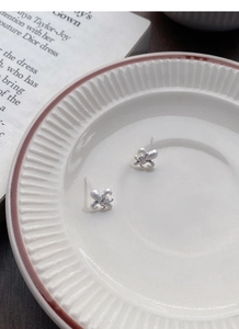 Macro detail of brushed S925 silver fleur-de-lis earrings with centered sparkling diamonds