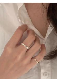 Detail of layered S925 sterling silver heart-shaped rings and minimalist band on finger