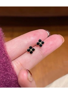 Close-up of four-leaf clover sterling silver studs with black stones held by hand