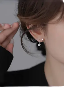 Dettaglio di orecchini a stella in argento con zircone indossati da una modella