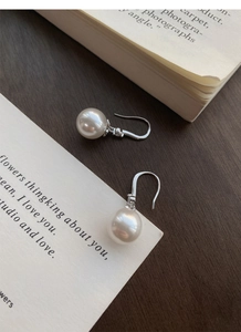 Détail de boucles d'oreilles en perles et argent S999 avec zircon sur table en bois