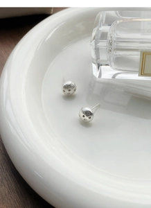 Close-up of S925 sterling silver brushed star earrings on a white ceramic tray